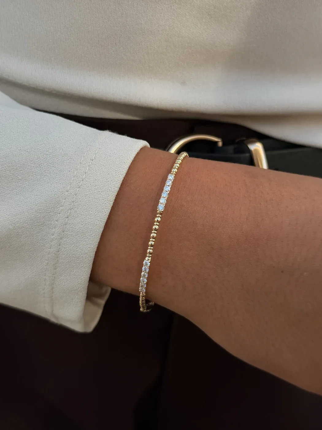 14k yellow gold diamond beaded flex bangle worn on the wrist with an ivory sleeve