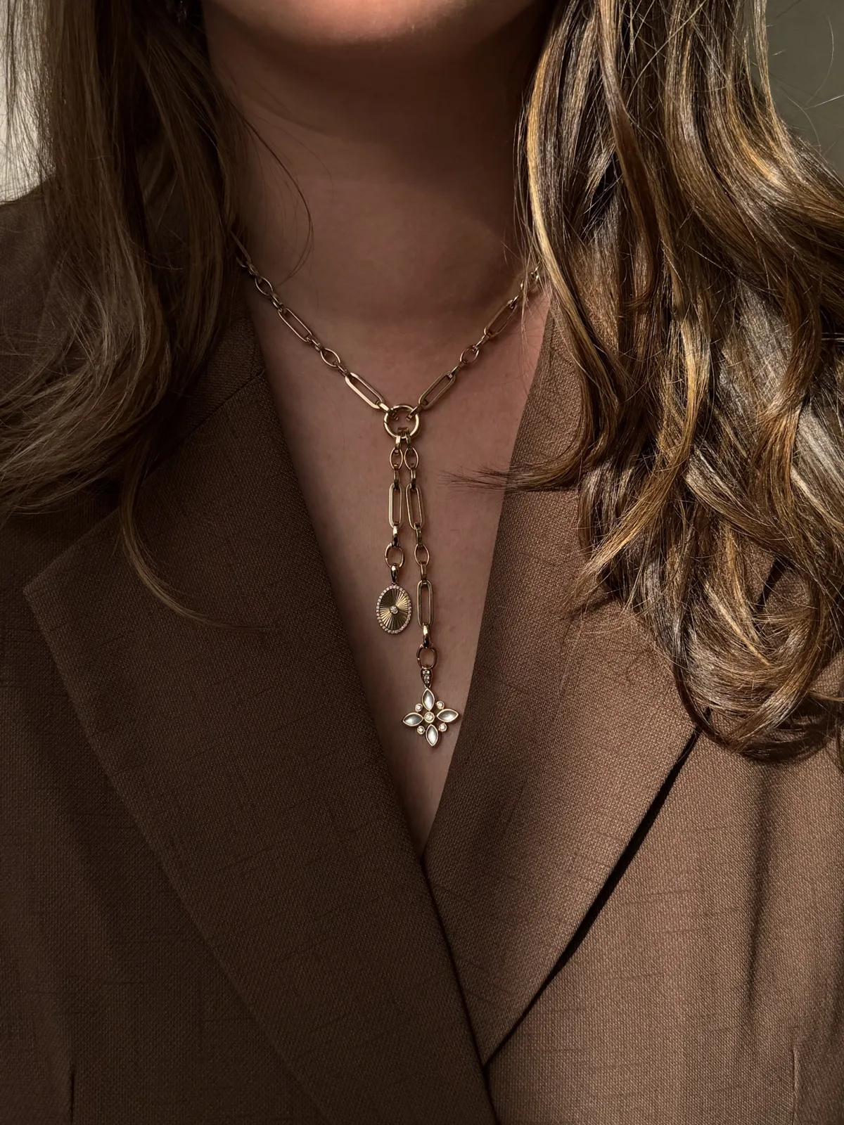14k yellow gold clip chain worn as a lariat, with two drop hinge clasps holding charms