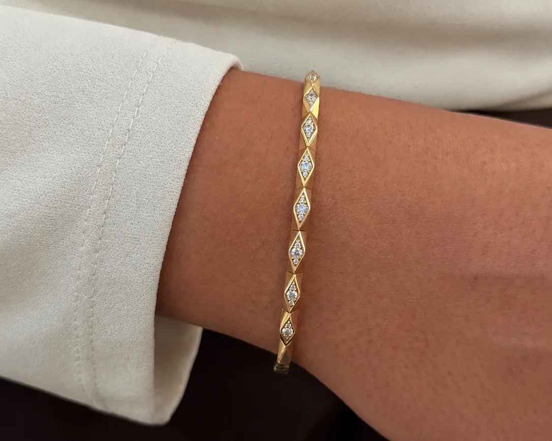 14k yellow gold geometric diamond flex bangle worn on the wrist with an ivory sleeve